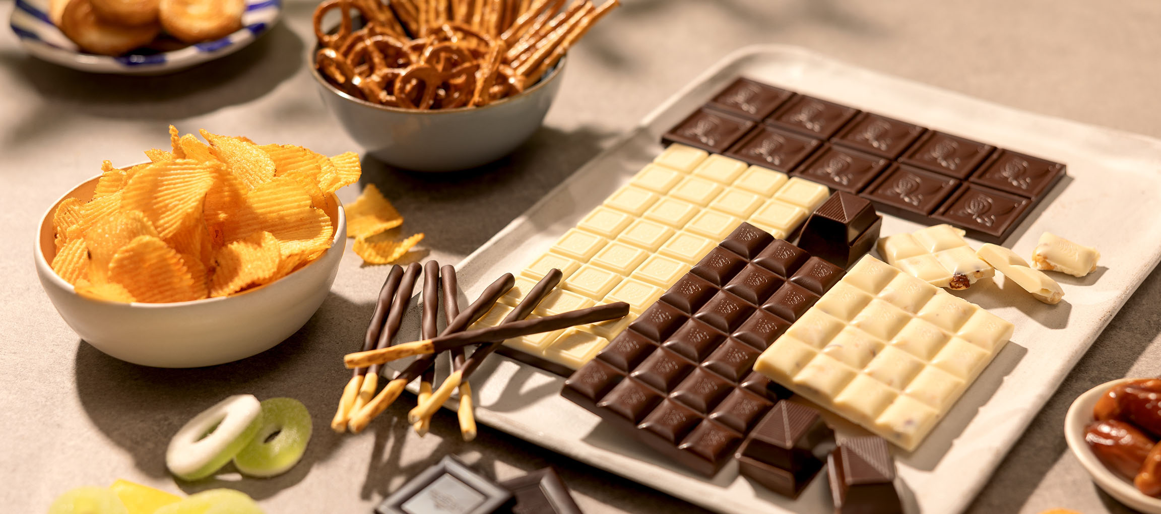 Cioccolatini assortiti, patatine, pretzel e caramelle su un tavolo.