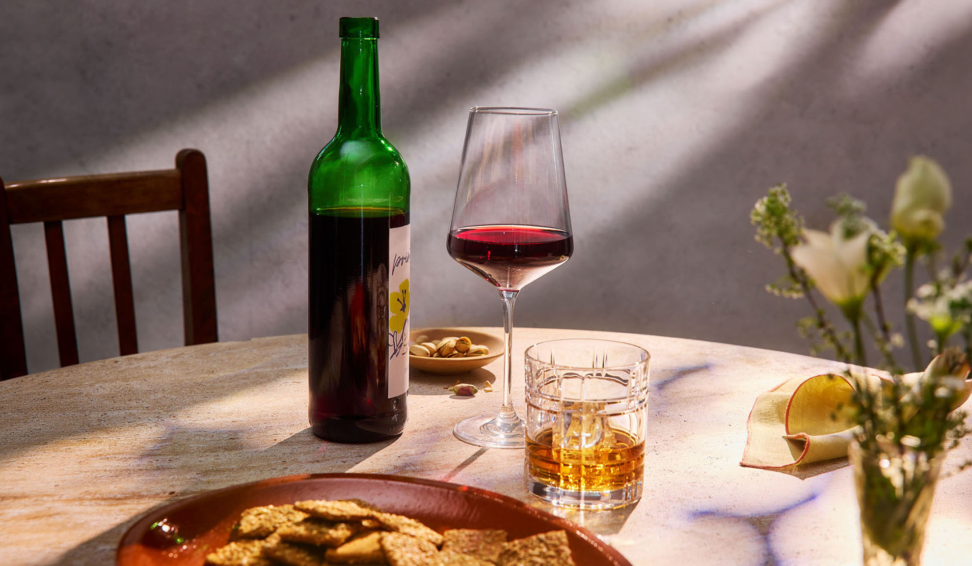 Vino rosso, whisky e snack su un tavolo al sole.