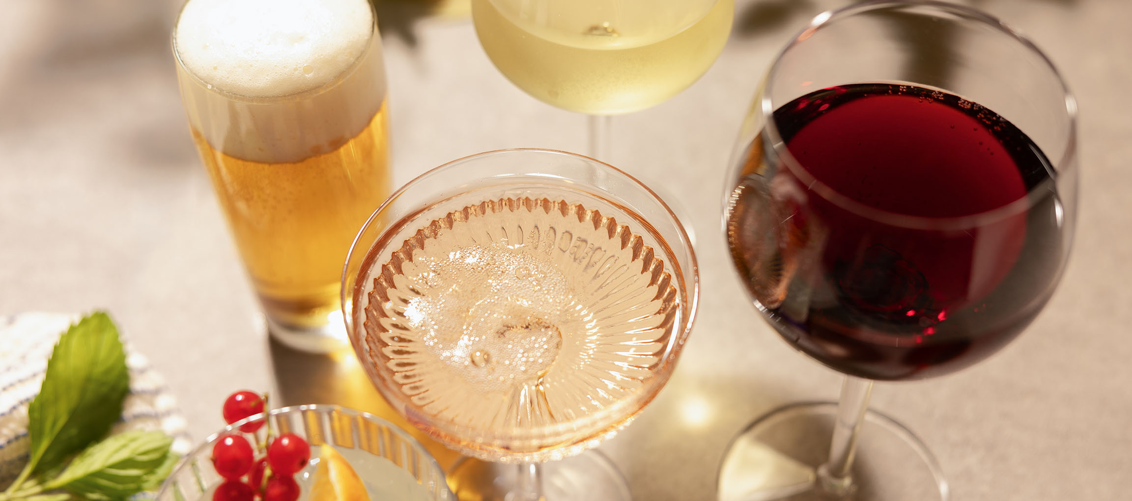 Birra, vino rosato e vino rosso in bicchieri, con bacche e menta.