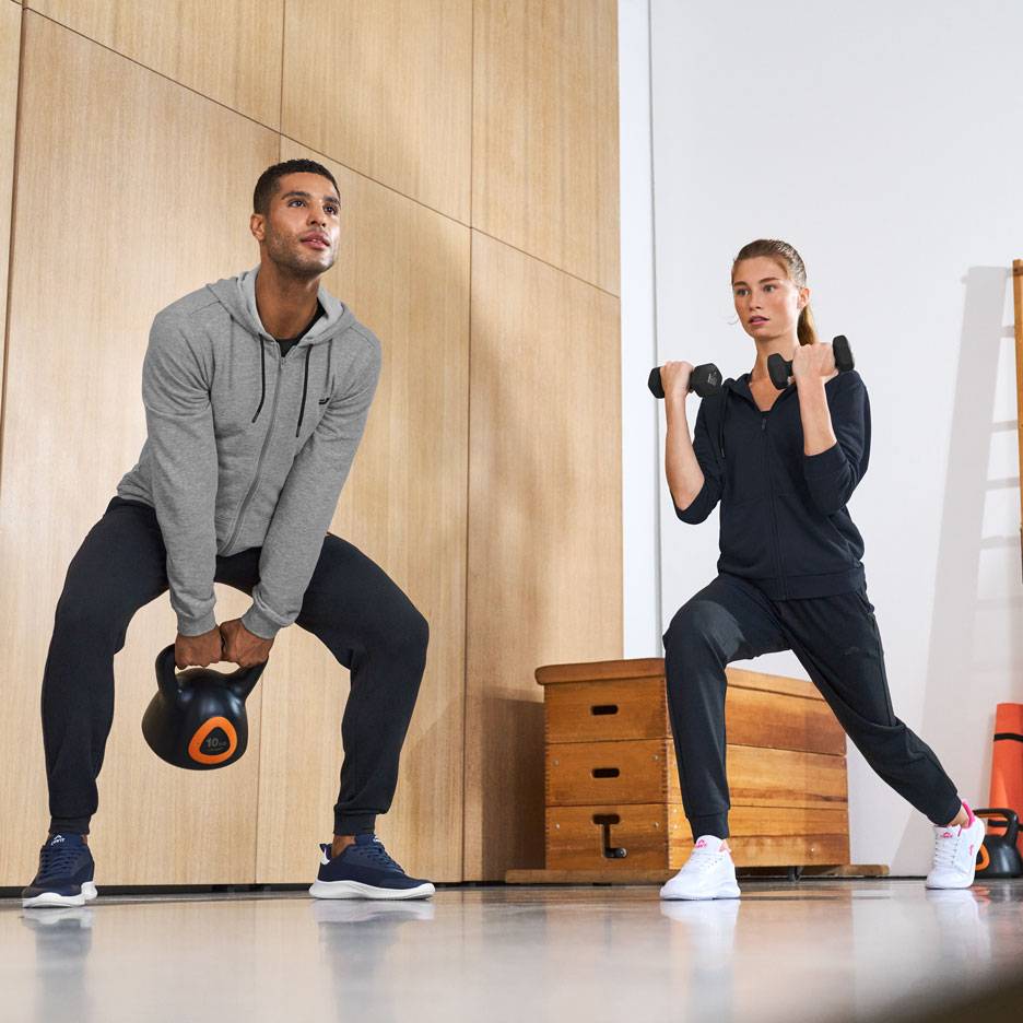 Uomo e donna in abbigliamento sportivo, si allenano con kettlebell e manubri.