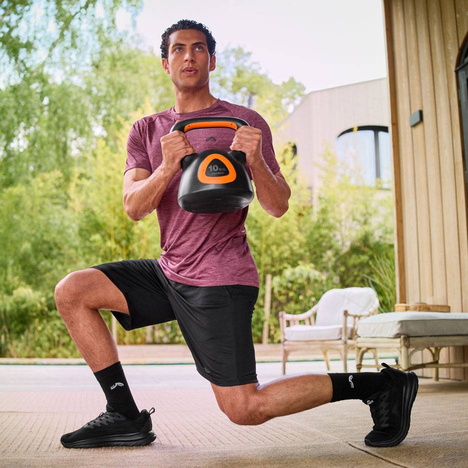Uomo che esegue affondi con una kettlebell da 10 kg all'aperto.