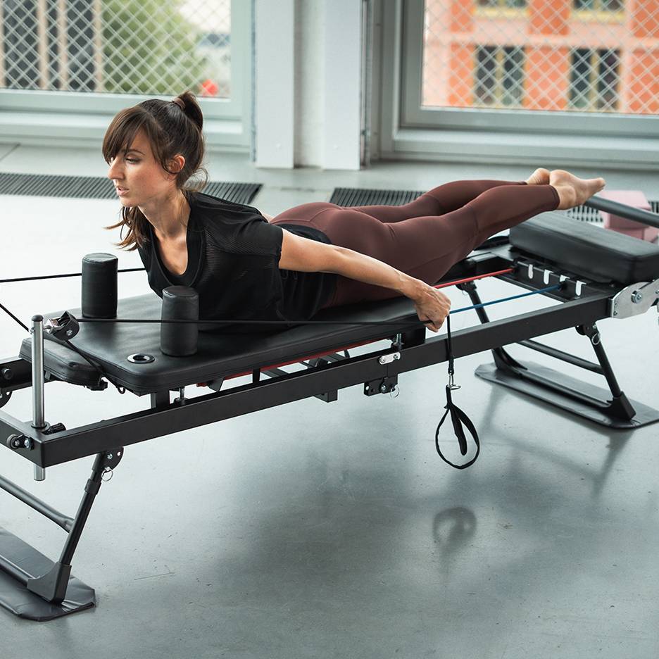 Donna che si allena su una macchina Pilates con fasce di resistenza.