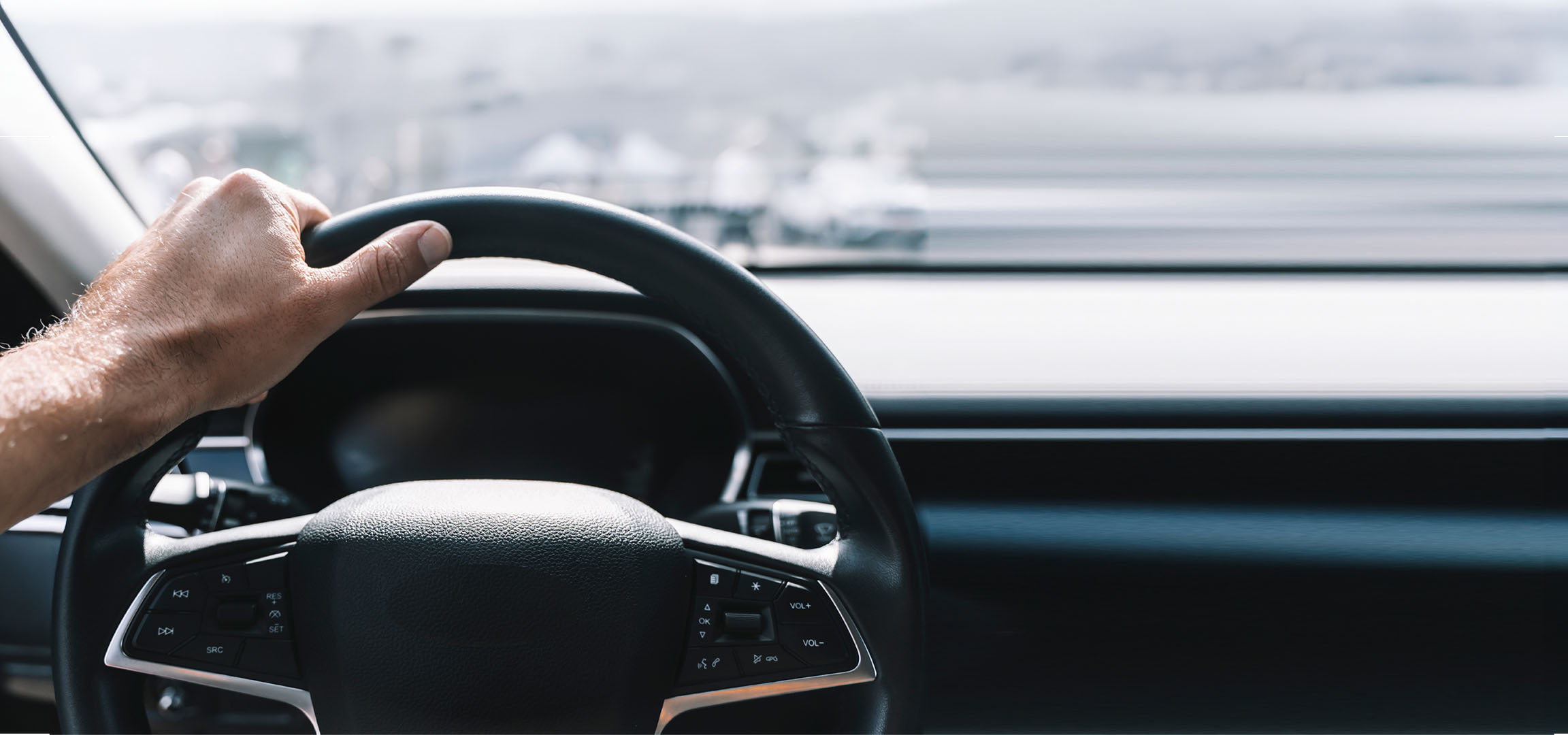 Mano di un uomo che tiene il volante di un'auto.