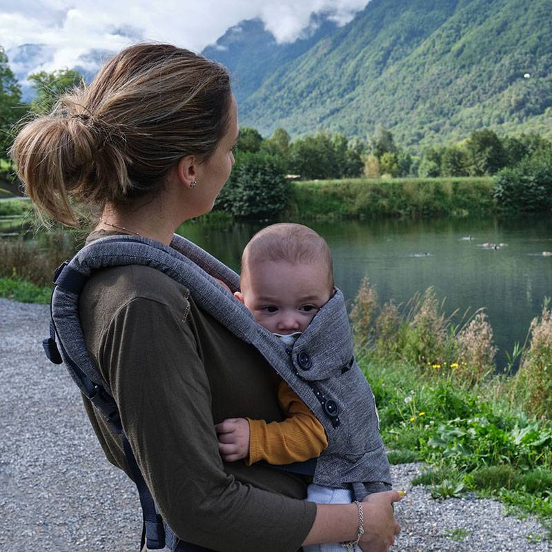 Mamma con bambino in marsupio all'aperto.