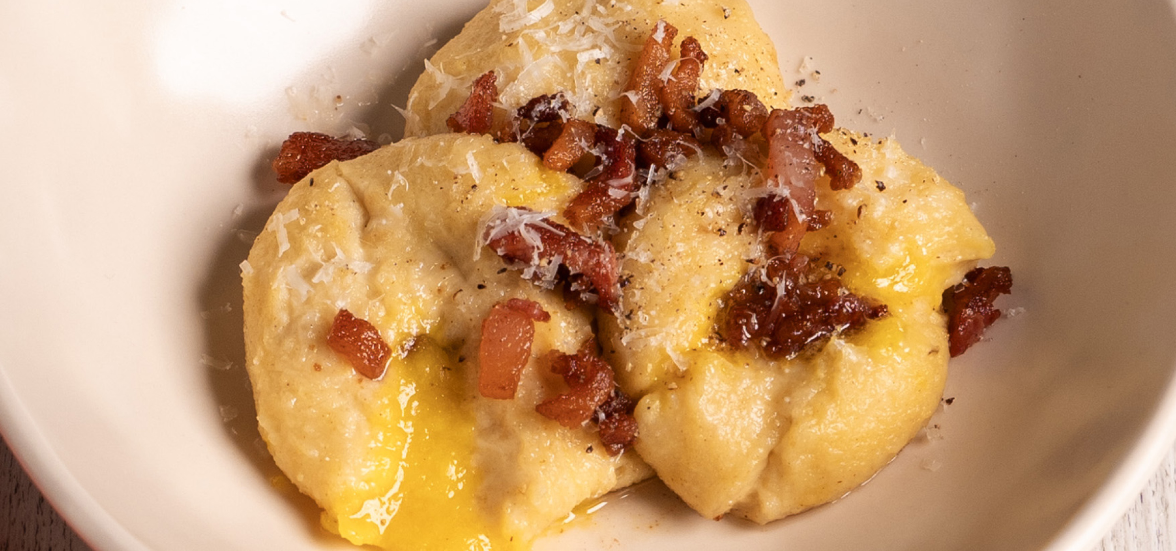 Gnocchi al formaggio con pancetta croccante e pepe nero.