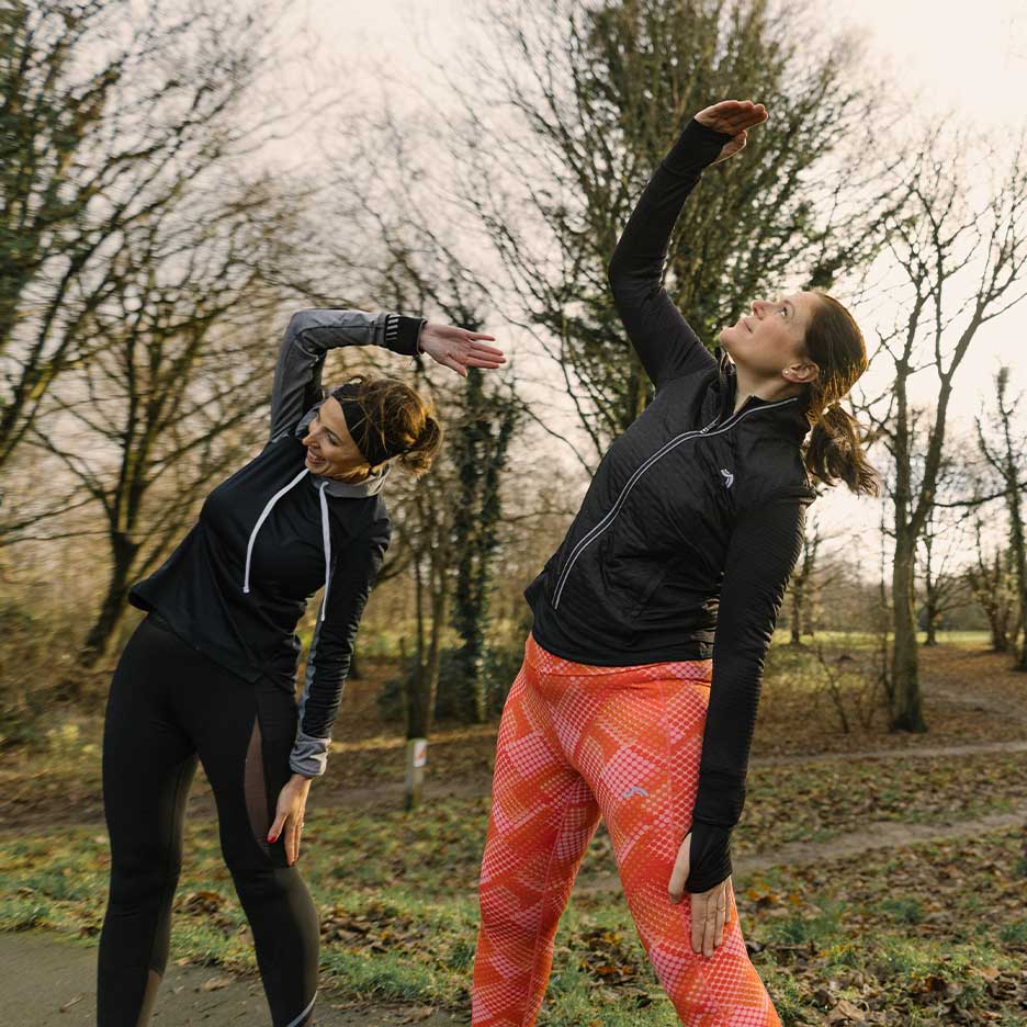 Due donne in abbigliamento sportivo si allungano all'aperto.