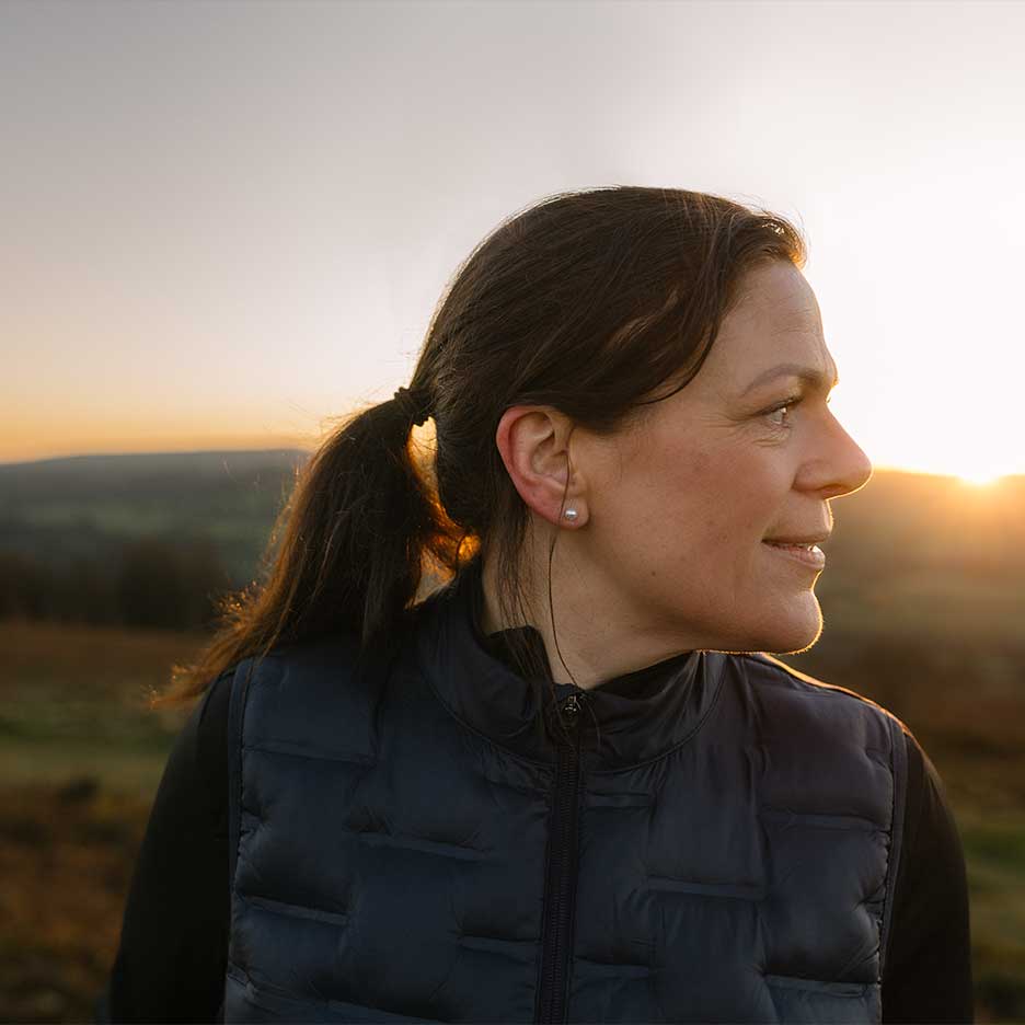 Donna con gilet nero e maglione nero al tramonto.