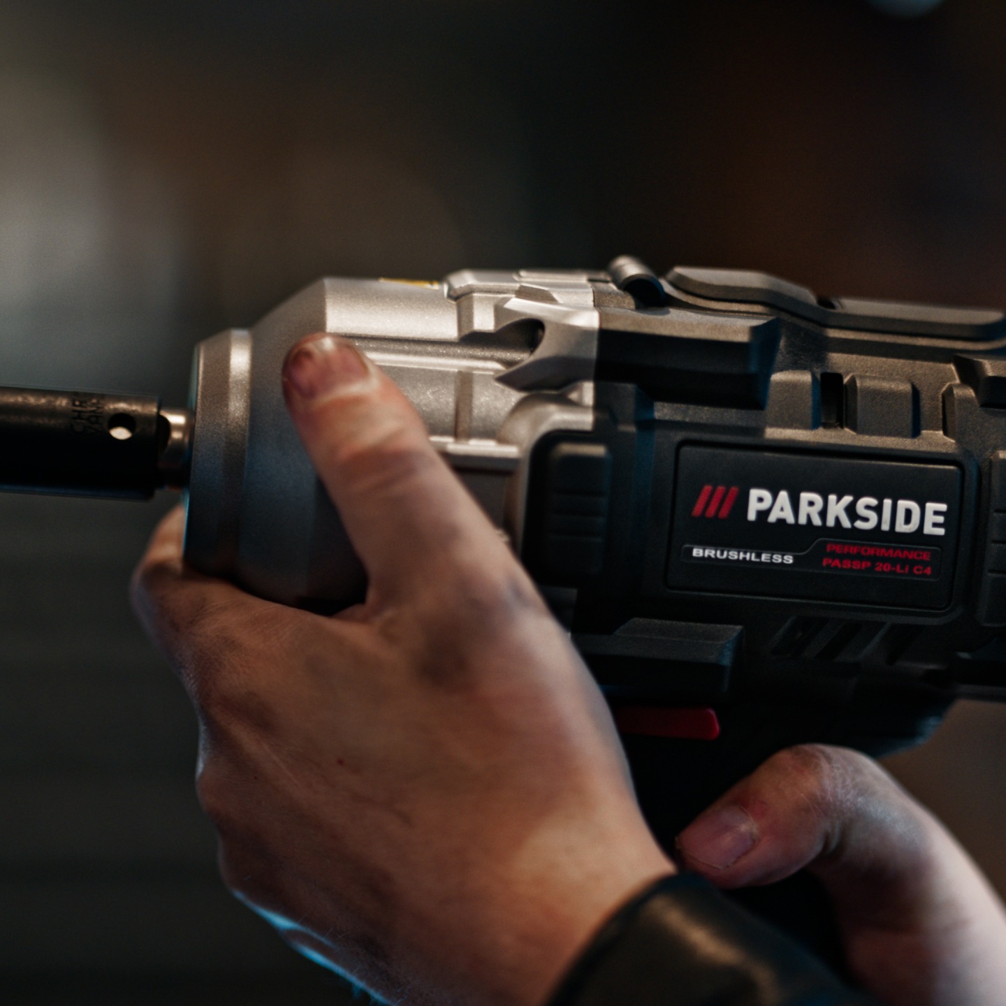 Una persona tiene un trapano avvitatore a impulsi Parkside Performance, con le mani sporche.
