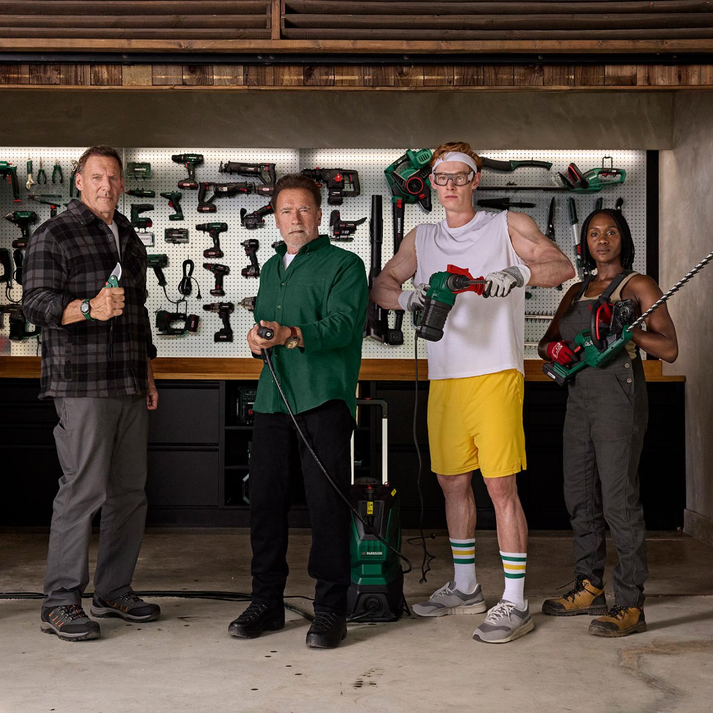 Quattro persone, incluso Arnold Schwarzenegger, posano con attrezzi Parkside in un'officina.