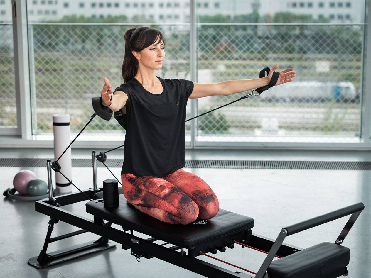Donna che fa Pilates su un reformer con fasce di resistenza.