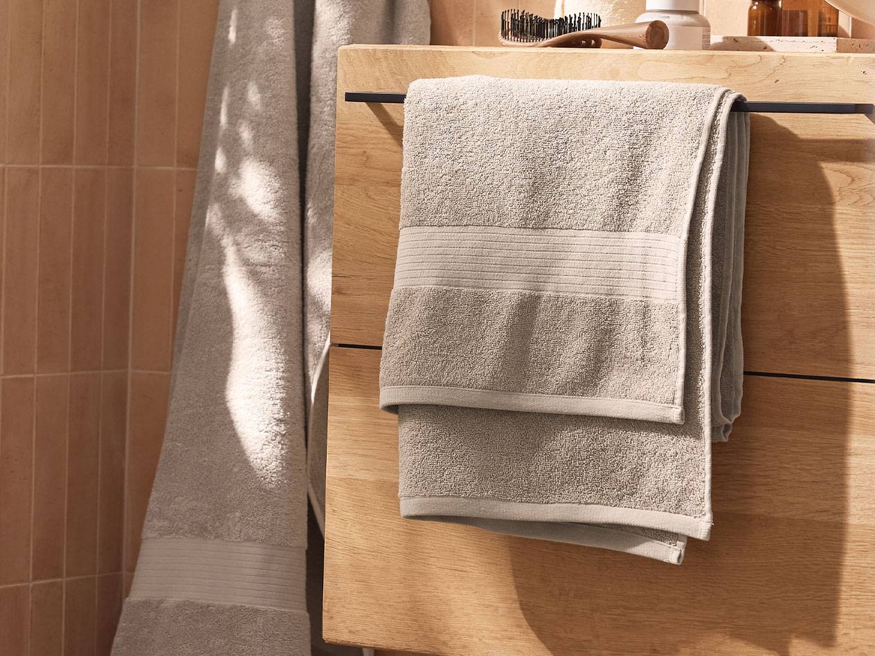 Asciugamani grigio chiaro appesi a un mobile di legno in un bagno.