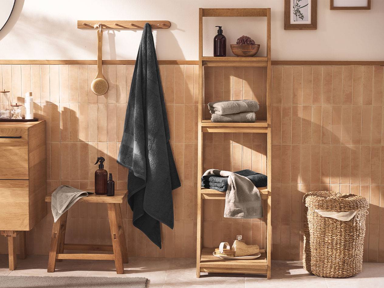 Bagno con asciugamani grigi, scaffali in legno e accessori da bagno.