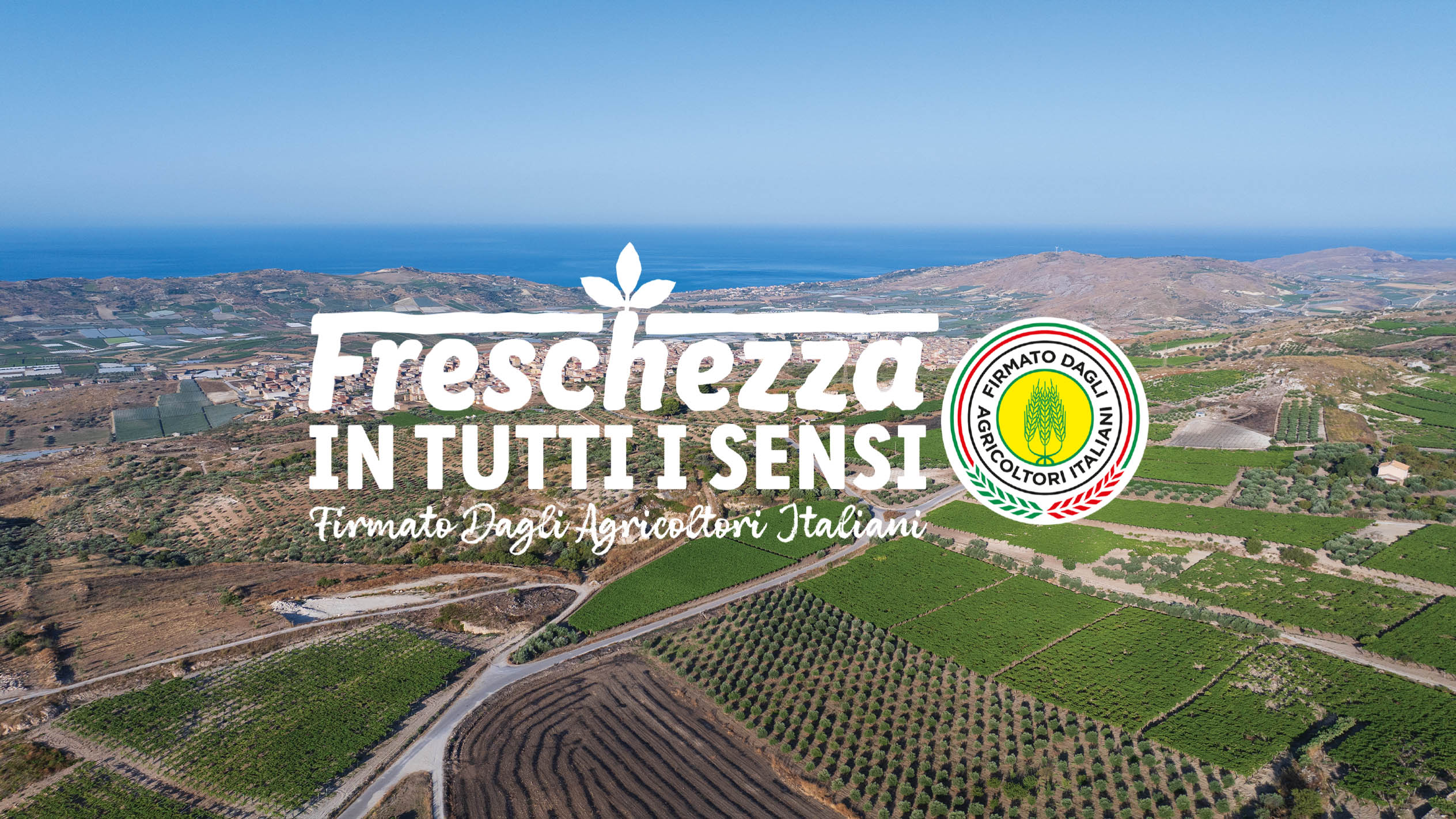 Paesaggio agricolo con campi verdi, mare e montagne, con testo 'Freschezza in tutti i sensi' e logo.