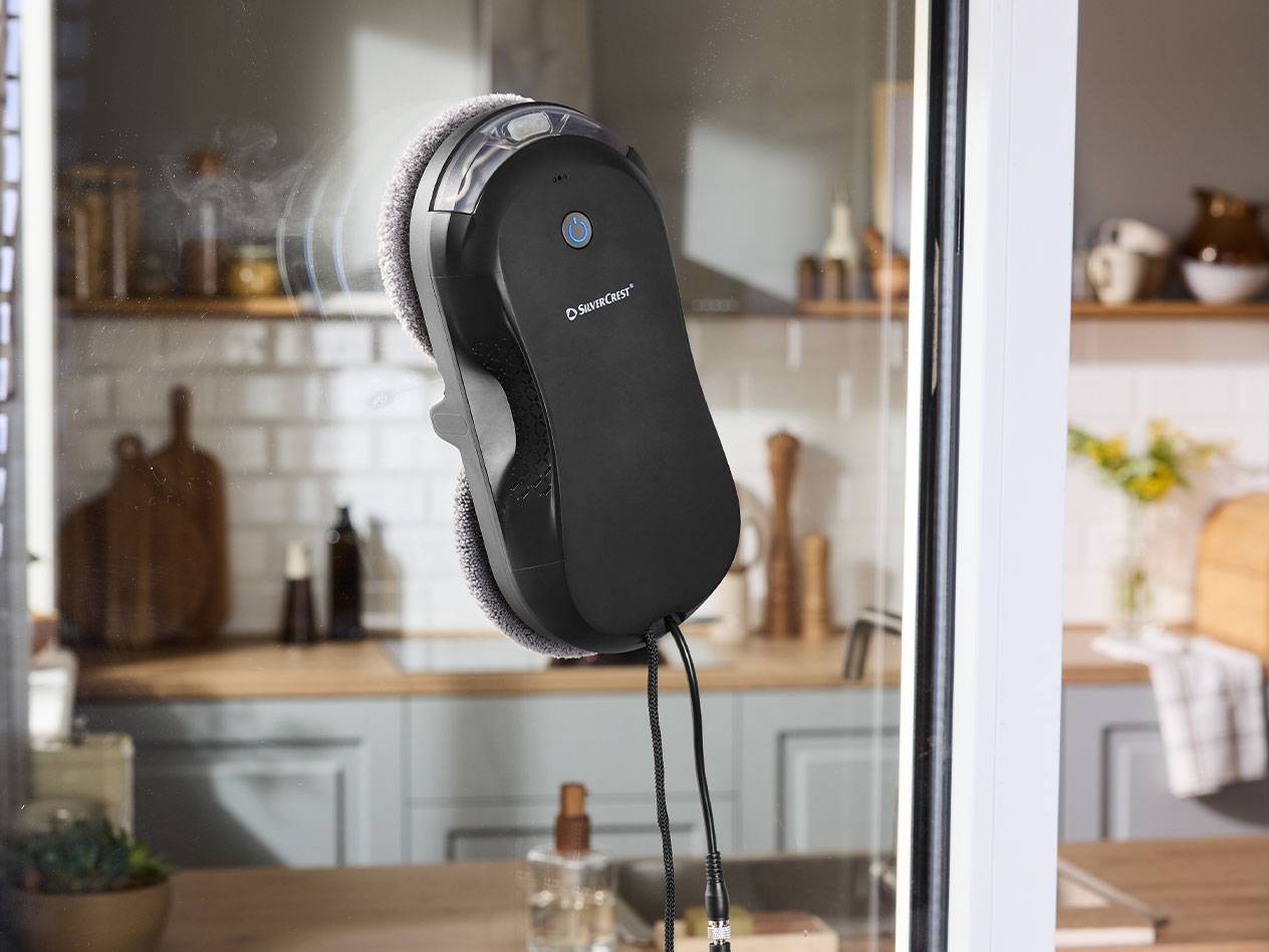 Robot lavavetri Silvercrest su un vetro con una cucina sullo sfondo.