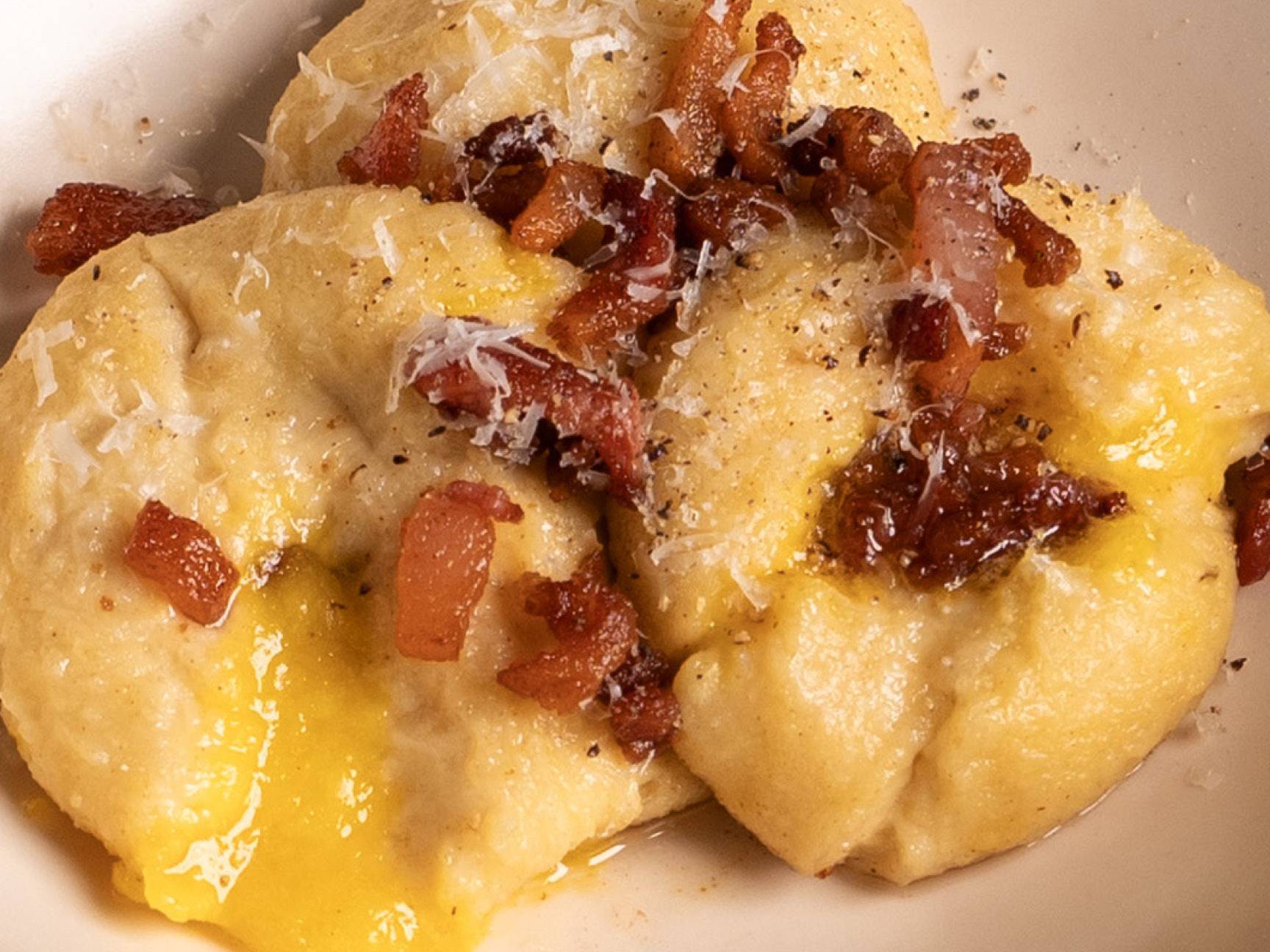 Gnocchi alla carbonara con pancetta croccante e formaggio grattugiato.