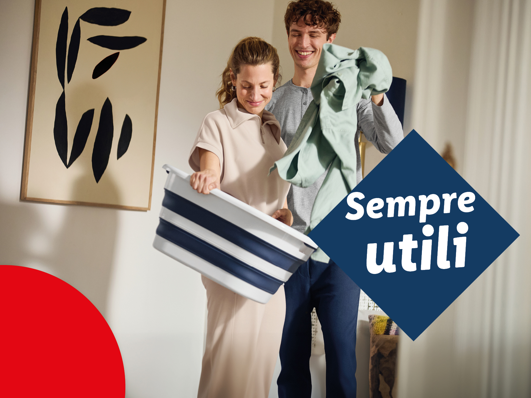 Una coppia sorridente con una cesta per il bucato pieghevole e vestiti.