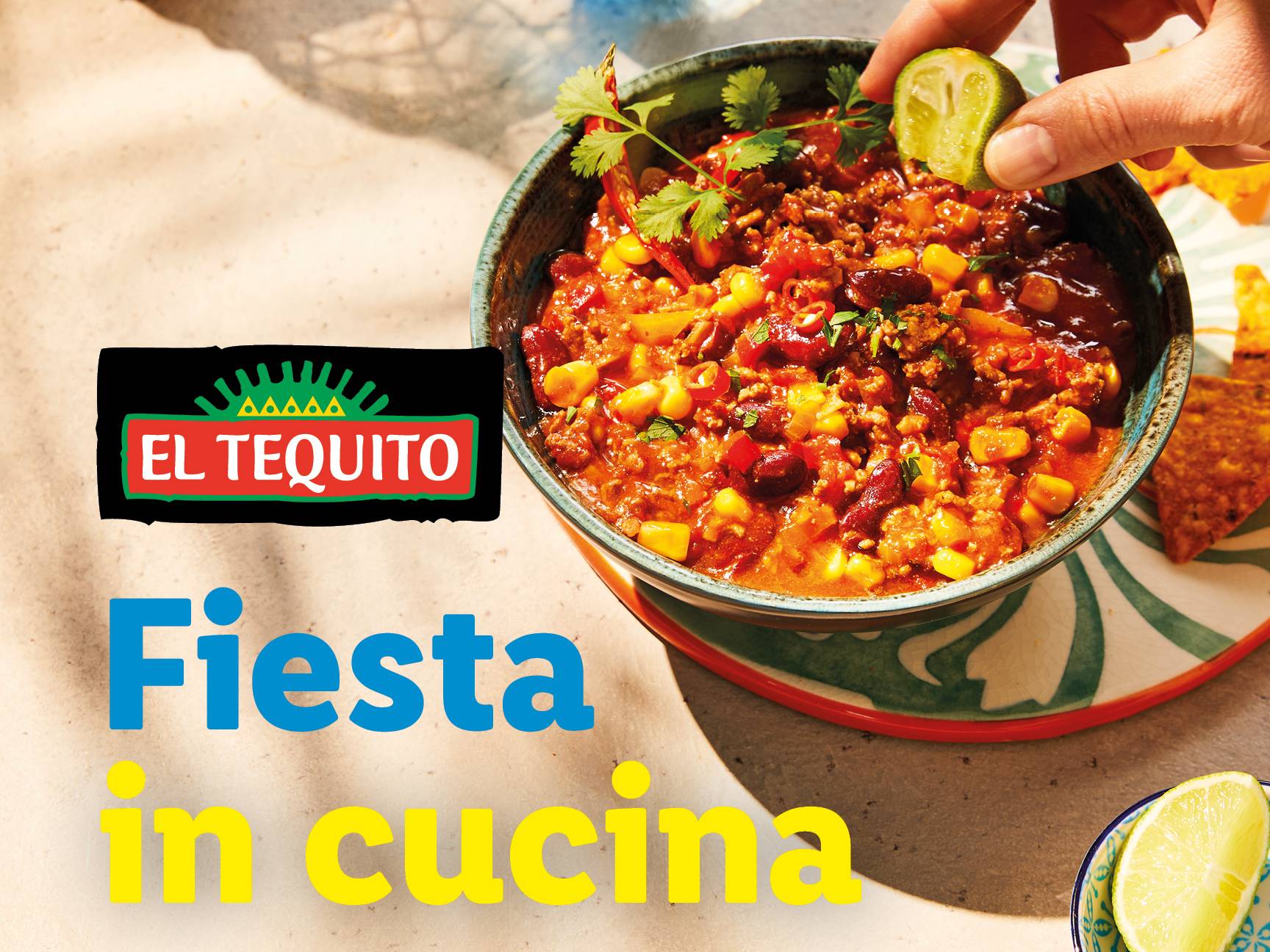 Una ciotola di chili con carne, mais e fagioli, con una mano che spreme il lime.