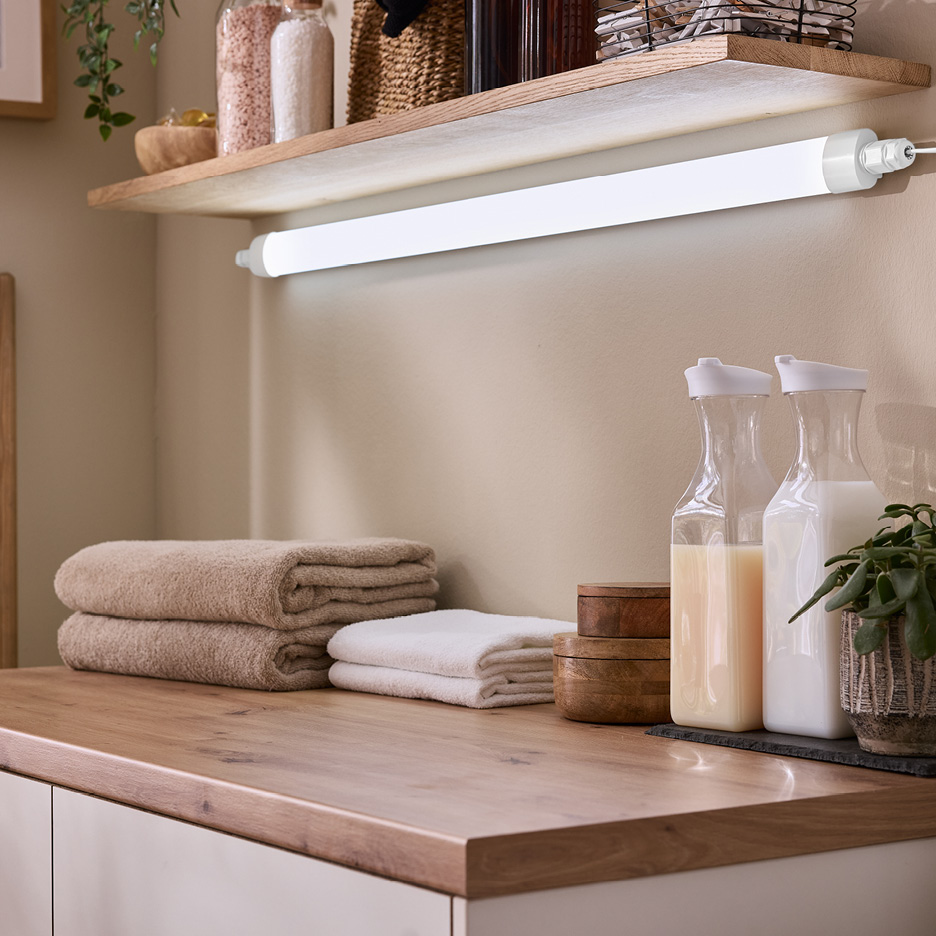 Un ripiano in legno con una lampada a LED, asciugamani e bottiglie di sapone liquido.