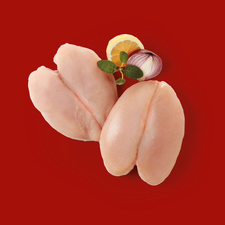 Due petti di pollo crudi con limone, cipolla rossa e erbe aromatiche su sfondo rosso.