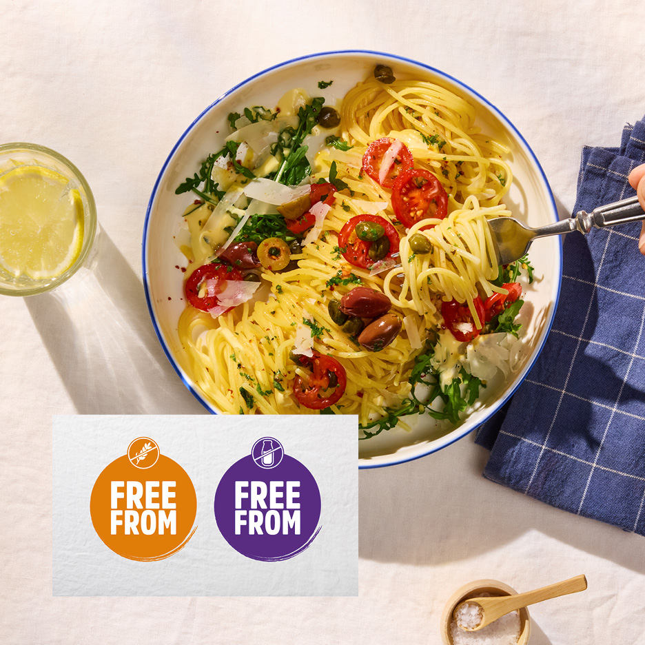 Spaghetti con pomodorini, olive e rucola, con etichette 'senza glutine' e 'senza lattosio'.