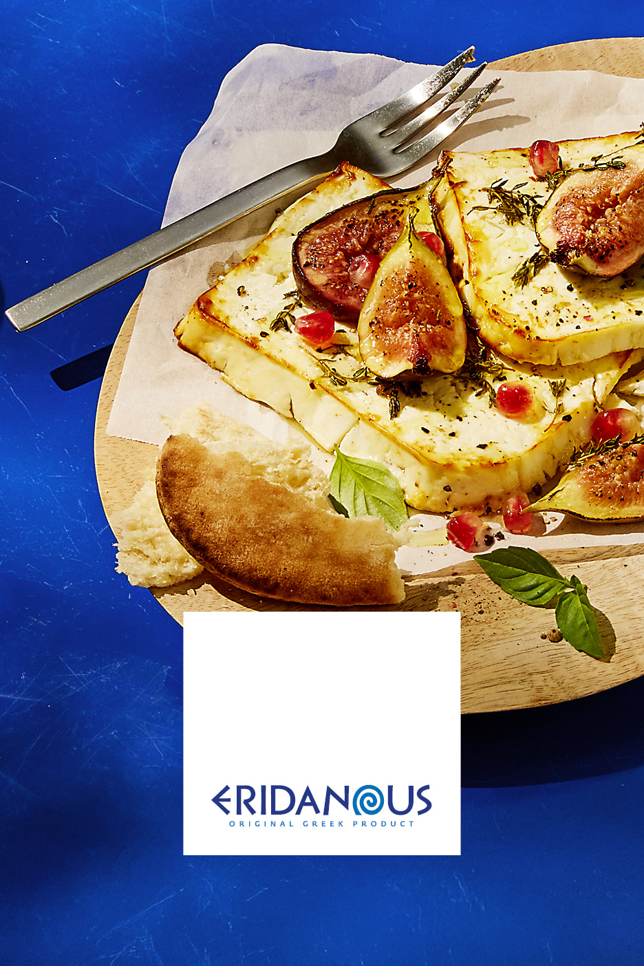 Formaggio greco Eridanous con fichi, melograno e pane su un tagliere di legno.