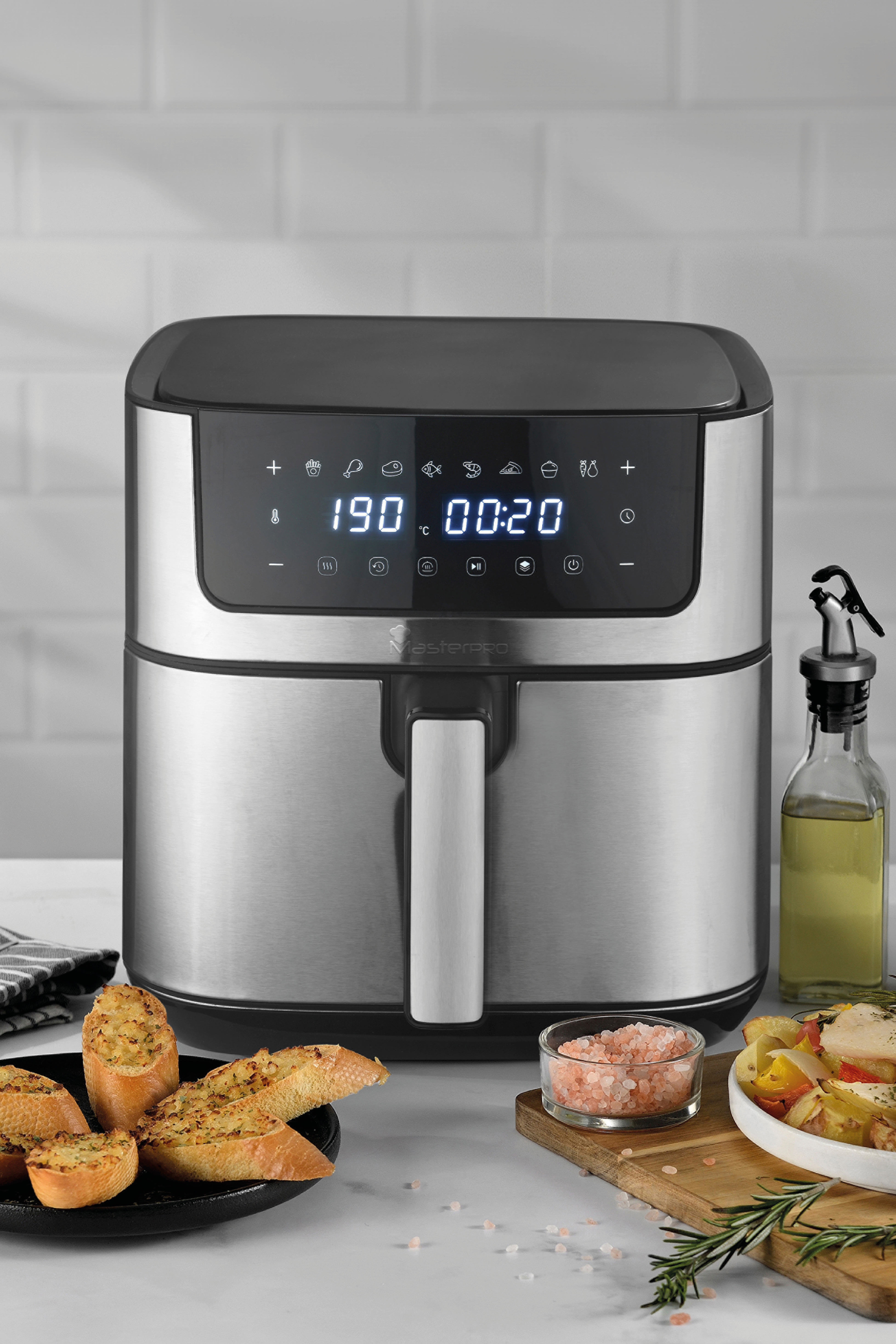 Friggitrice ad aria con display digitale, aglio pane, sale rosa e verdure arrostite.