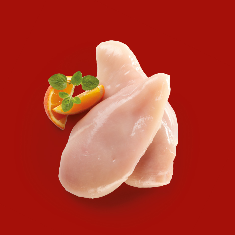 Filetti di petto di pollo crudi con spicchi d'arancia e origano su sfondo rosso.