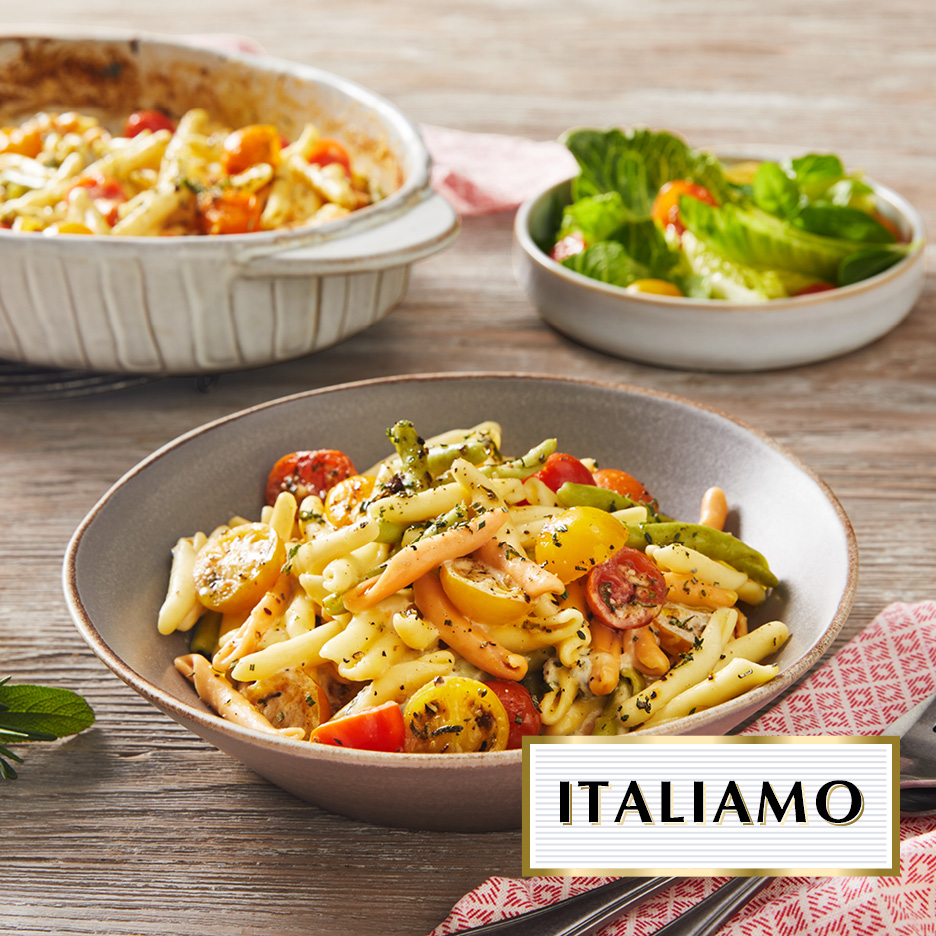 Pasta con pomodorini e insalata su un tavolo di legno, con la scritta 'ITALIAMO'.