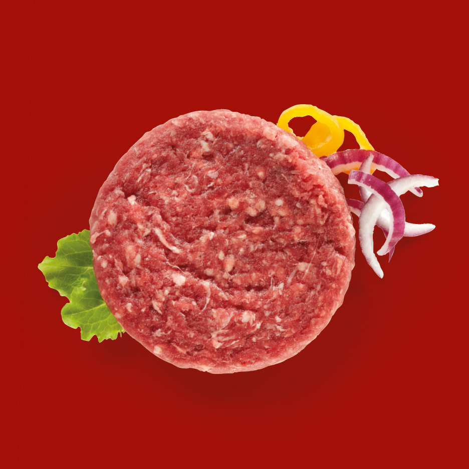 Hamburger di carne cruda con lattuga, cipolla rossa e peperoni gialli su sfondo rosso.