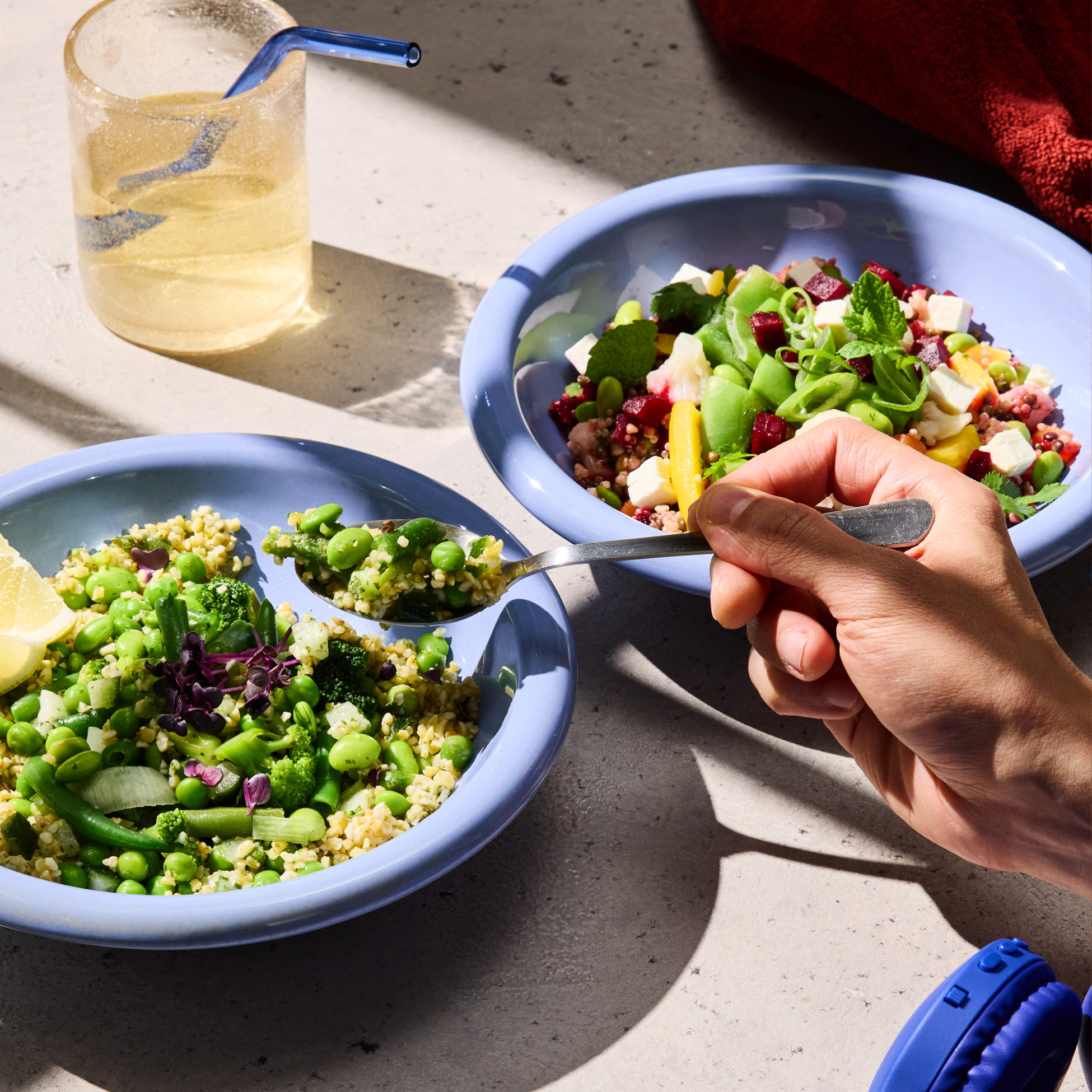Due ciotole di insalata colorata con cereali, verdure e formaggio, una bevanda e cuffie.