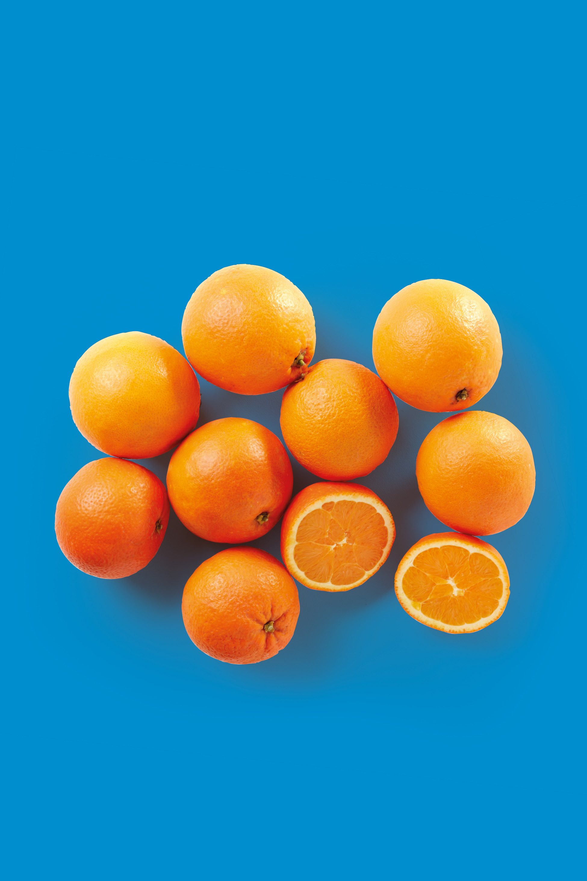 Arance intere e tagliate a metà su sfondo blu.