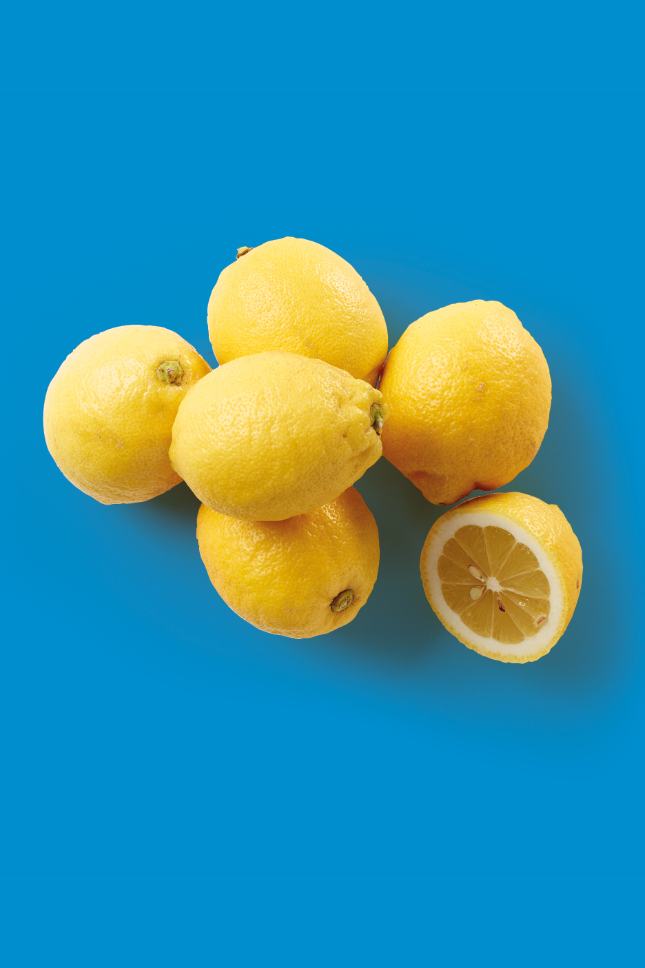 Limoni freschi e gialli su sfondo blu, uno tagliato a metà.