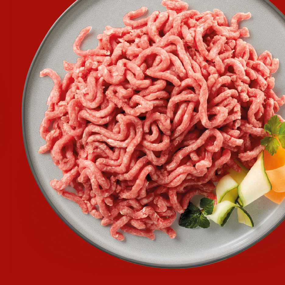 Carne macinata fresca su un piatto grigio con guarnizione di verdure.