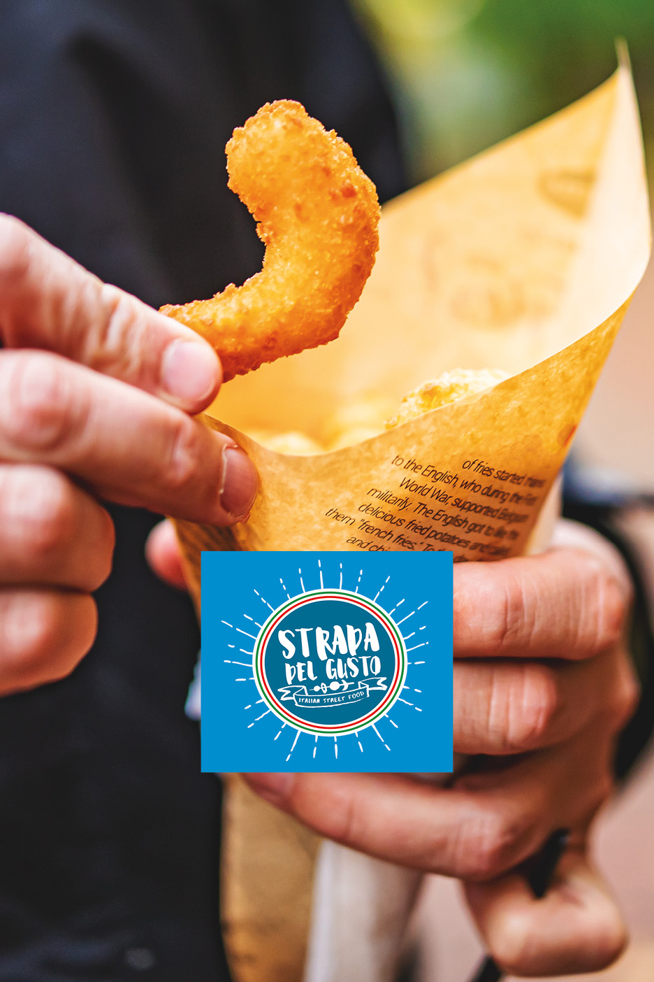 Mano che tiene una patatina fritta da un cono di carta con testo stampato.