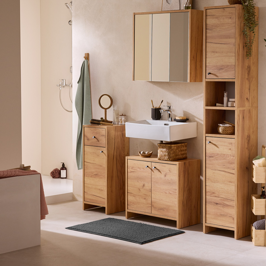 Mobili da bagno in legno chiaro con lavabo bianco, specchio e doccia.