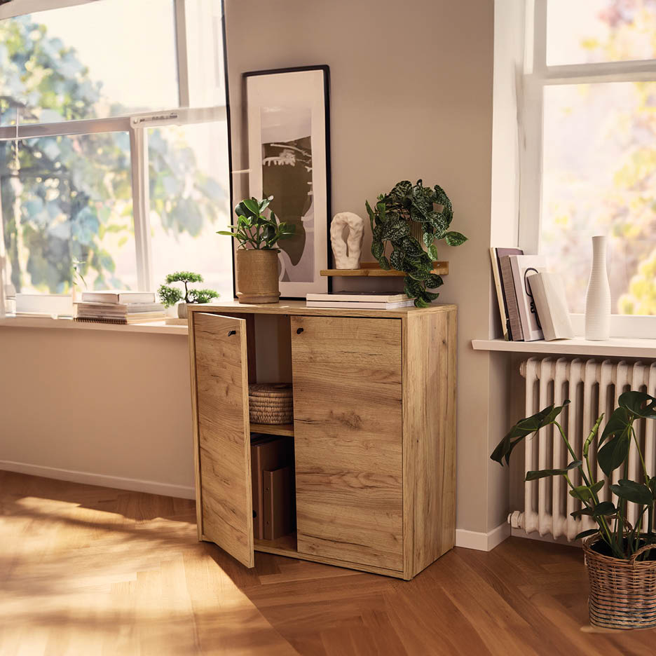 Credenza in legno chiaro con ante aperte, piante e decorazioni in un soggiorno luminoso.