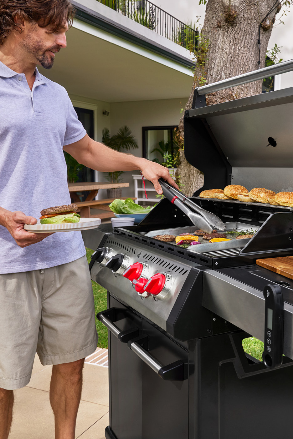 Uomo che griglia hamburger e panini su un barbecue da esterno.