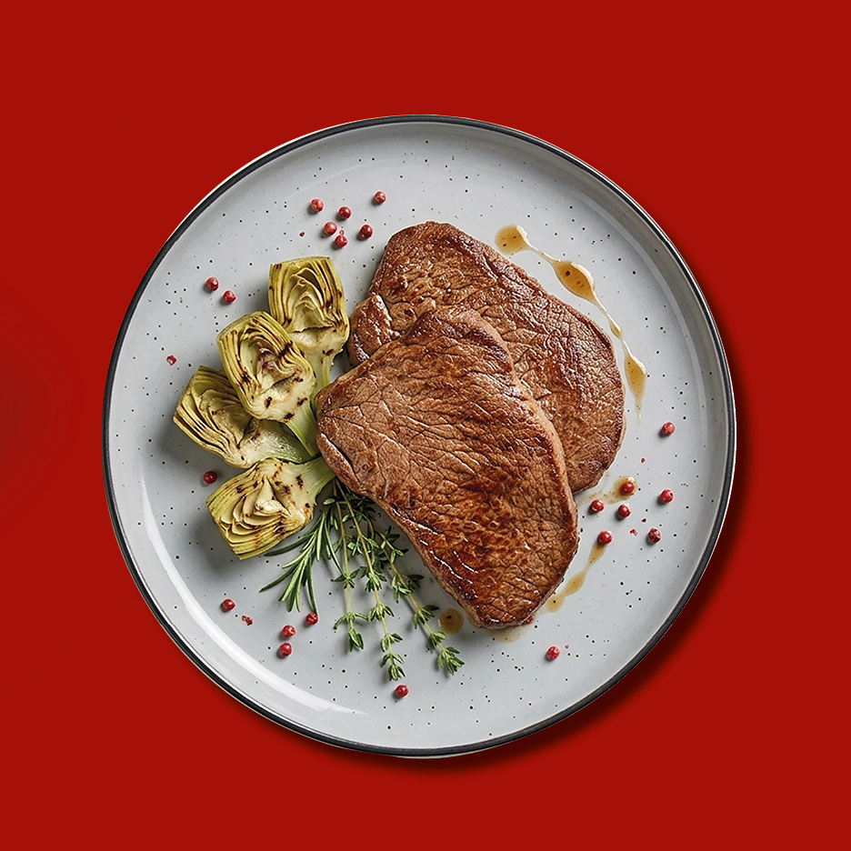 Bistecche di manzo con carciofi e rosmarino su un piatto.