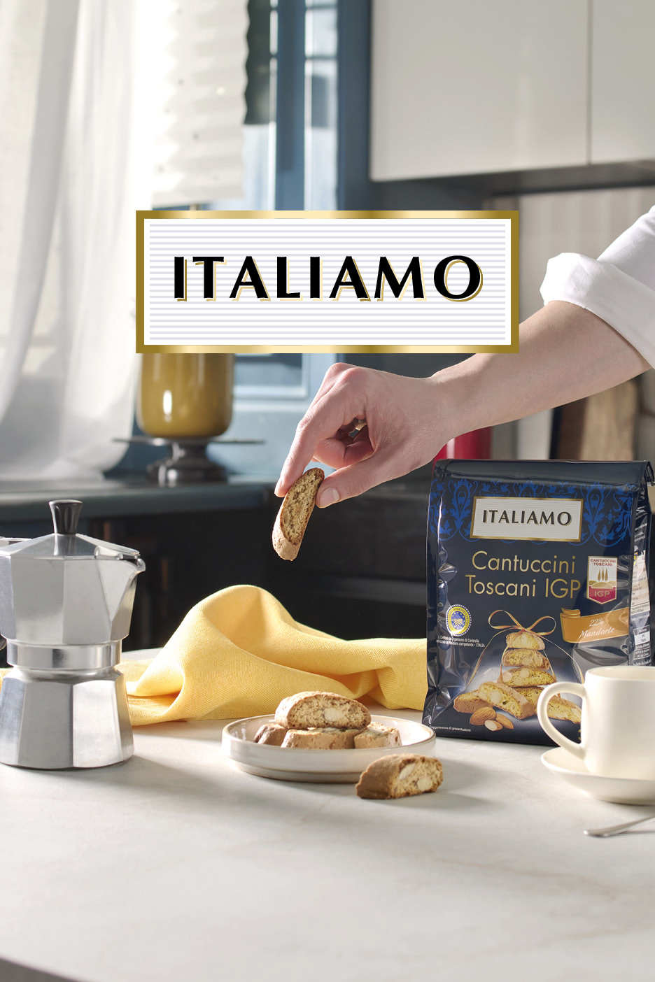 Mano che prende un cantuccino da un sacchetto di biscotti, con caffettiera e tazza.