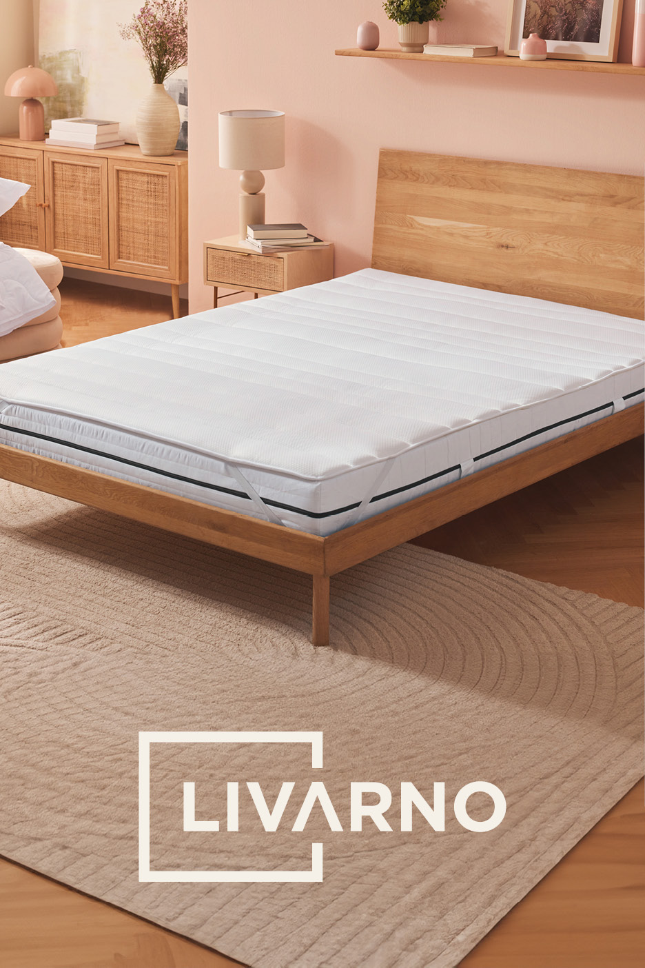 Materasso e topper su letto in legno, con comodino e cassettiera in una camera da letto dai toni caldi.