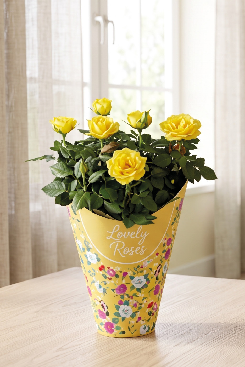 Vaso di rose gialle con confezione decorata con la scritta 'Lovely Roses' su un tavolo di legno.