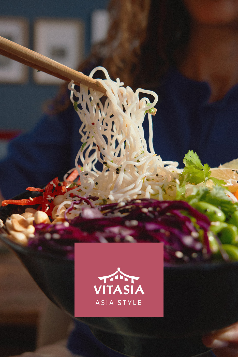 Noodles asiatici con verdure fresche e arachidi, presi con le bacchette.