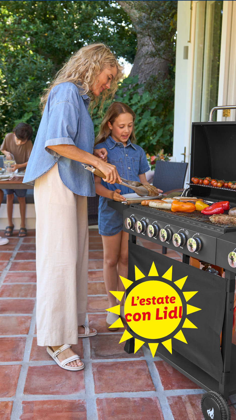 Donna e bambina grigliano carne e verdure su un barbecue in giardino. Testo: L'estate con Lidl!