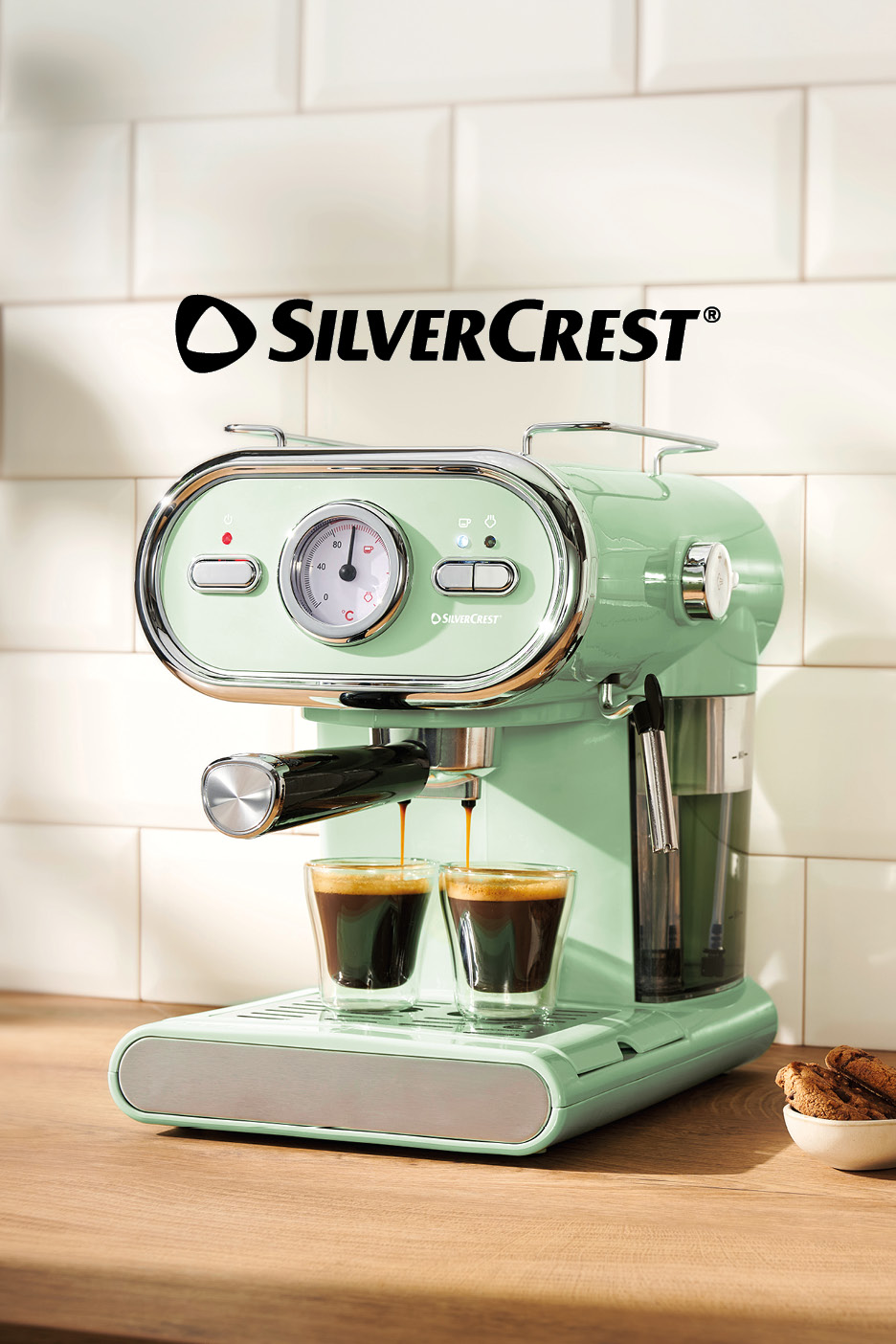 Macchina da caffè verde menta che eroga due espressi in bicchieri su un bancone di legno.