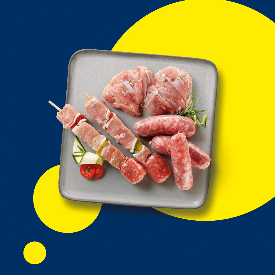 Spiedini di carne e salsicce su un piatto grigio, con sfondo blu e giallo.