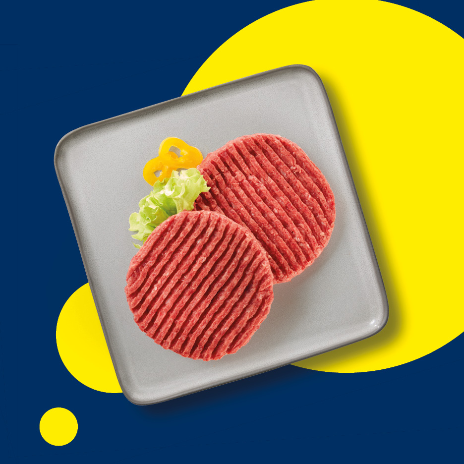 Due hamburger di carne cruda su un piatto grigio con guarnizione di lattuga e peperoni gialli.