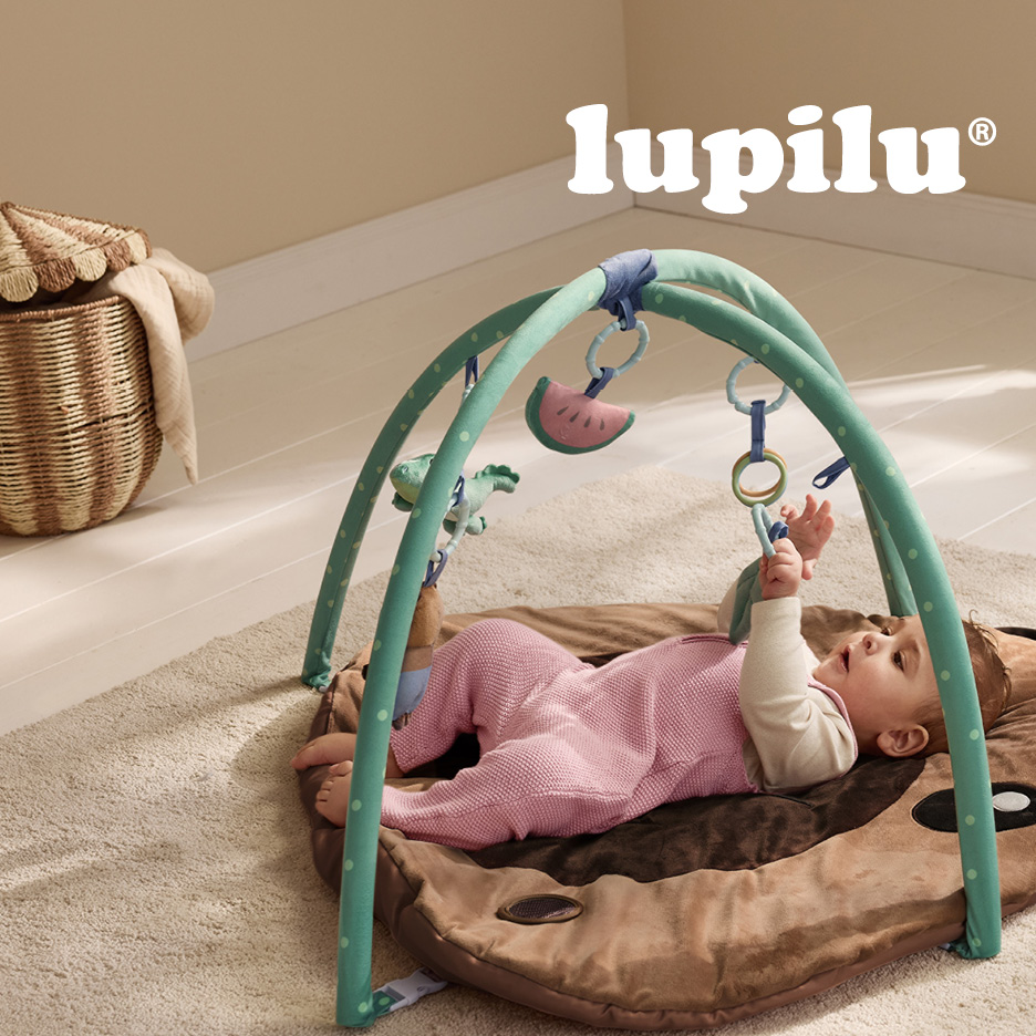 Bambino su tappeto gioco con arco attività e giocattoli pendenti.