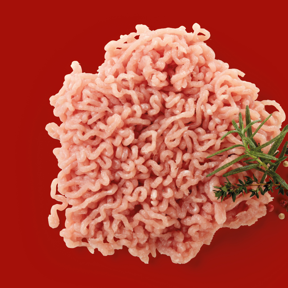 Carne macinata di pollo o tacchino con rosmarino e timo su sfondo rosso.