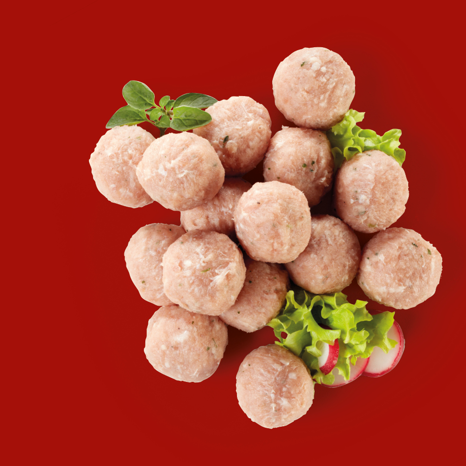 Polpette di carne crude con guarnizione di lattuga, ravanelli e origano su sfondo rosso.