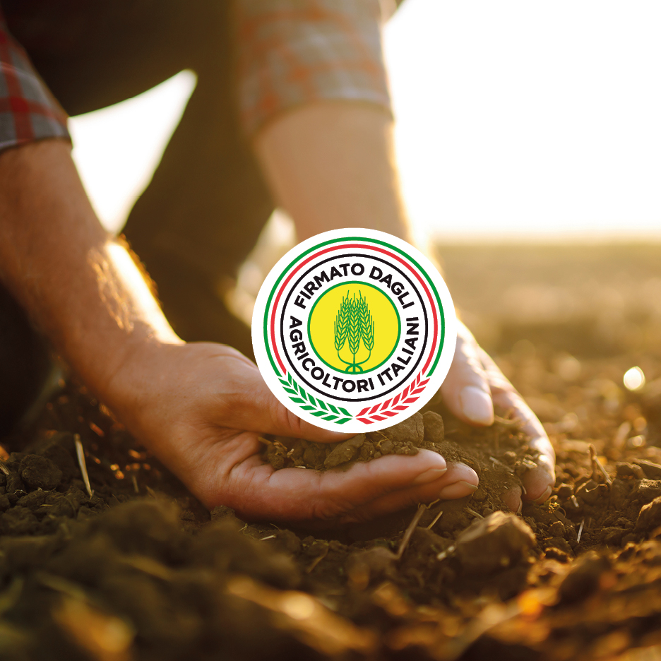 Mani di un agricoltore che tengono la terra con un logo circolare che recita 'Firmato dagli Agricoltori Italiani'.